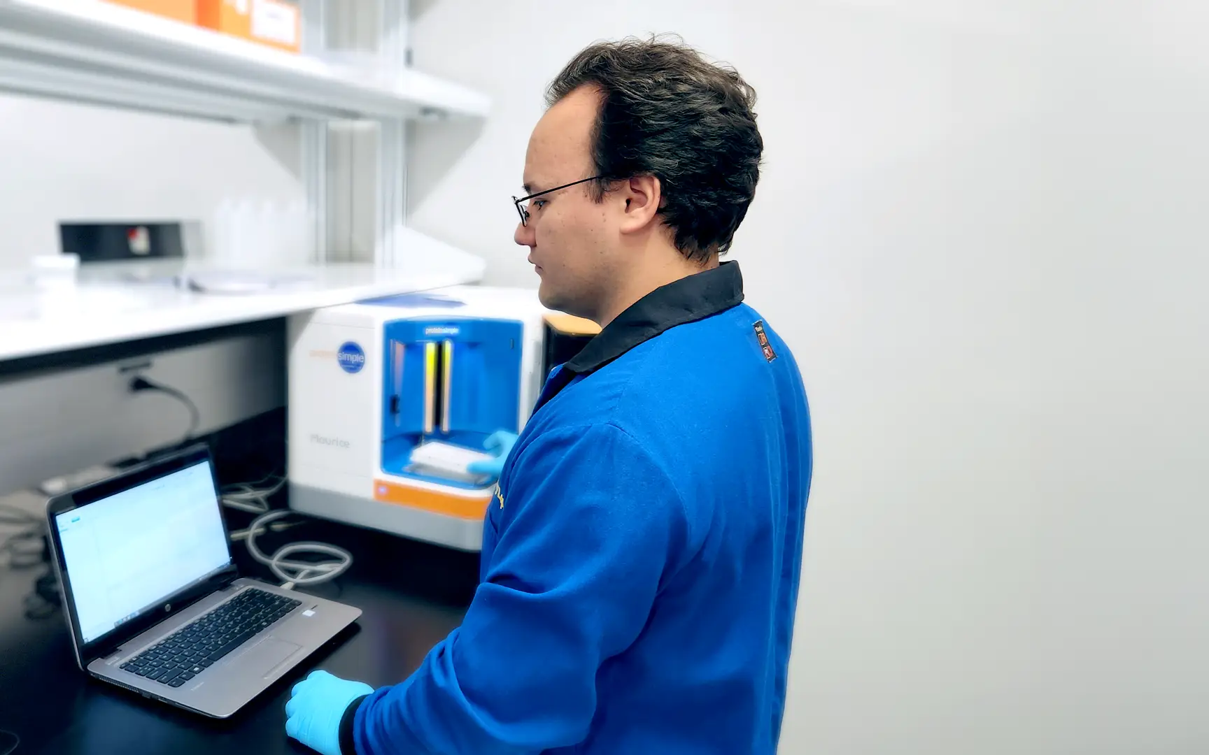 Technician working in at computer in cleanroom environment at Xcellon Biologics